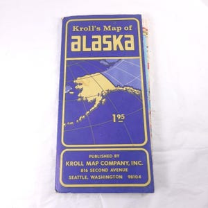 May include: A vintage map of Alaska, titled "Kroll's Map of Alaska," with a blue and gold color scheme. The map features a detailed outline of Alaska and includes the publisher's information: Kroll Map Company, Inc., Seattle, Washington.