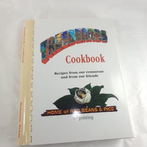 May include: A cookbook titled "Treebeards Cookbook" with a white cover. The cover features the title in colorful letters, the word "Cookbook" in red, and a floral illustration. The spine reads "Treebeards Cookbook, Houston, Texas."
