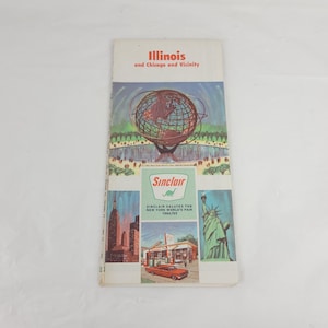 May include: A vintage travel brochure titled Illinois and Chicago and Vicinity featuring a graphic of the Unisphere, the Sinclair logo with a green dinosaur, the Statue of Liberty, a city skyline, and a red car at a gas station from 1964/65.