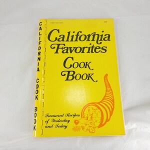 May include: A vintage cookbook titled "California Favorites Cook Book" with a bright yellow cover. The cover features the title in elegant script, a cornucopia illustration, and the text "Treasured Recipes of Yesterday and Today."
