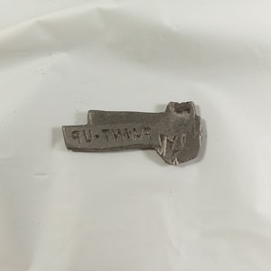 May include: A silver-colored metal key with the words "PAINT UP" engraved on it.