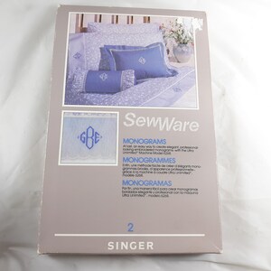 May include: A box for Singer SewWare monogramming instructions. The box features a blue and white floral pattern with a blue pillow and a white pillow with a blue monogram. The text on the box reads "SewWare" and "MONOGRAMS".