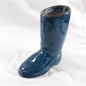 May include: A blue ceramic boot-shaped planter. The planter has a glazed finish and is perfect for small plants or succulents.