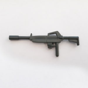 May include: A dark gray plastic toy gun with a handle and a barrel. The gun has a futuristic design.