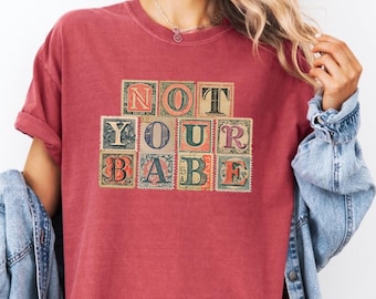 Camiseta "Not Your Babe", camiseta con estampado vintage, camiseta feminista, camiseta con cita atrevida, camiseta con tipografía retro, camiseta de moda para mujer, camiseta con actitud.