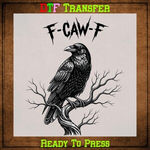 May include: Black and white graphic of a raven perched on a tree branch. The raven is detailed with textured feathers and a sharp beak. The text "F-CAW-F" is above the raven, and "READY TO PRESS" is below. The words "DTF TRANSFER" are at the top.