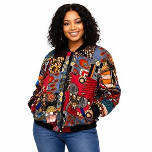 May include: A bomber jacket featuring a vibrant patchwork design with various geometric and organic patterns in shades of red, blue, orange, and black. The jacket has a black ribbed collar, cuffs, and hem, with a central black zipper closure.