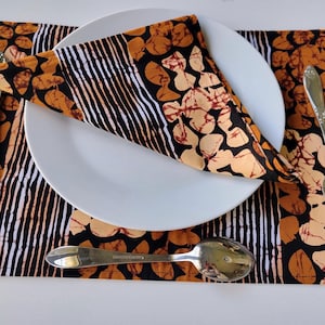 Könnte beinhalten: Ein braunes und schwarzes gemusterter Platzdeckchen mit einem weißen Teller, einem silbernen Messer, einer silbernen Gabel und einem silbernen Löffel. Das Platzdeckchen hat ein geometrisches Muster mit orange, braun und schwarzen Farben.