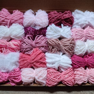 Packung rosa und weißes Garn. Verschiedene Gewichte, Arten und Texturen. Zum Weben und vieles mehr.