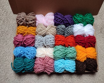 May include: A box filled with 20 balls of yarn in various colors, including red, blue, green, yellow, white, and brown. The yarn is arranged in two rows of ten balls each.