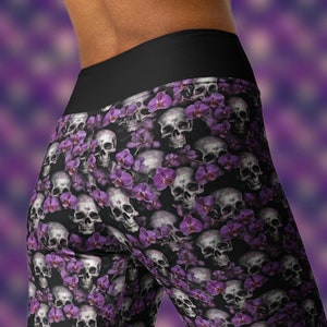Może przedstawiać: Legginsy w fioletowo-biały wzór z czaszkami i orchideami. Legginsy mają czarną gumkę w pasie.