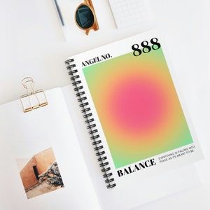 May include: A spiral-bound notebook with a colorful gradient design. The cover features the text "ANGEL NO. 888 BALANCE" with a pink, yellow, and green aura design. The text "EVERYTHING IS FALLING INTO PLACE AS ITS MEANT TO BE" is also visible.
