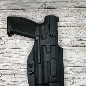 May include: A black handgun with a black holster. The holster has two black screws on the side.