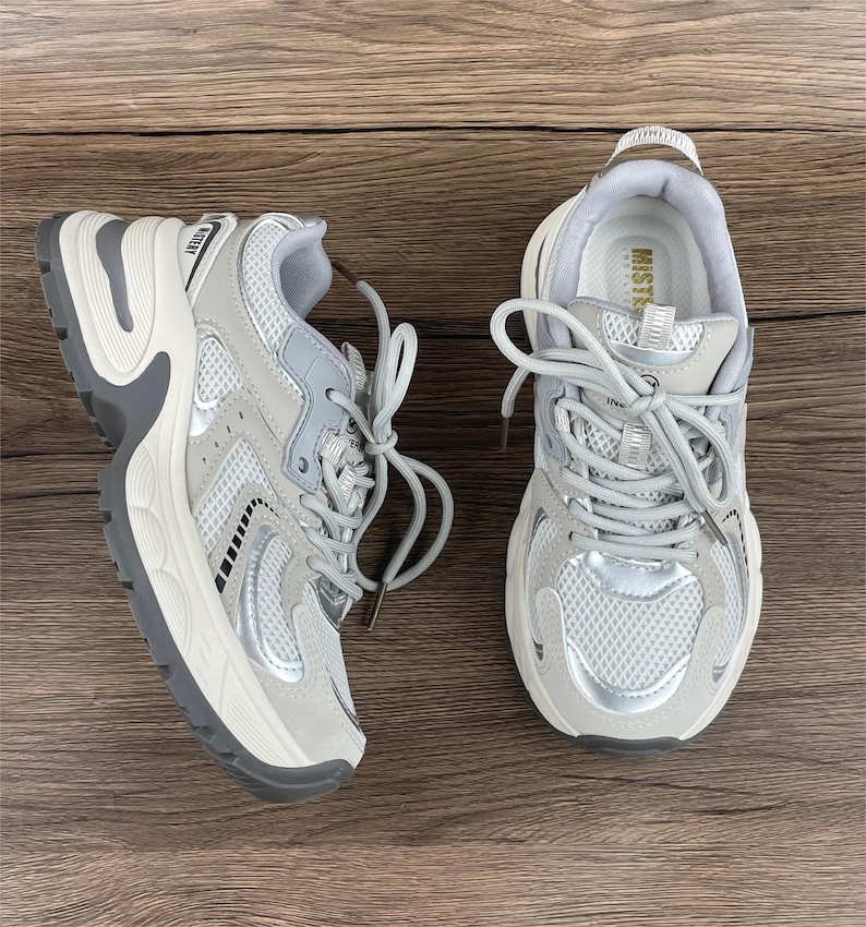 May include: A pair of grey and white trainers with a mesh upper and a chunky white sole. The trainers have a silver accent on the side and the word "Mister" is printed on the tongue.