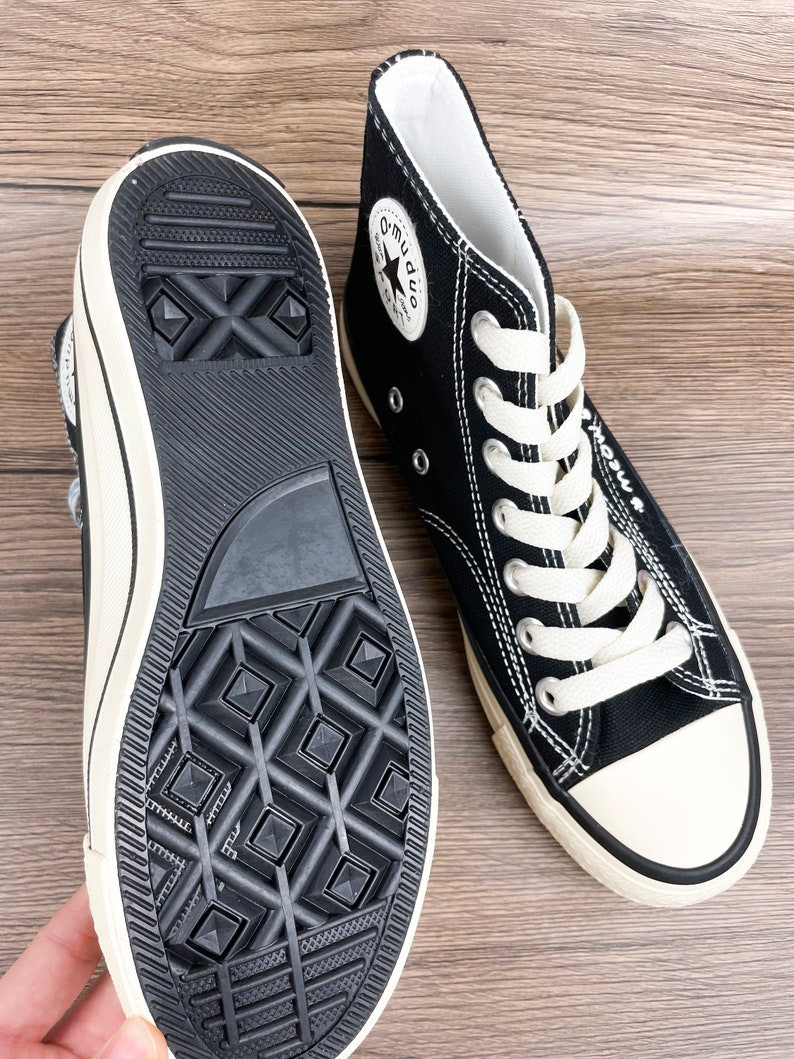 May include: Black high-top canvas sneakers with white laces and a white star logo on the side. The shoes have a black rubber sole with a diamond pattern.