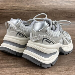 May include: A pair of grey and silver trainers with a chunky white sole. The trainers have a mesh upper and the word "MISTERY" is printed on the side of each shoe.