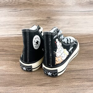 May include: A pair of black high-top canvas sneakers with white stitching. One shoe features a black star with the text "a.mudao Sport" and the other shoe has a cartoon graphic of a stack of cute animals with the text "Know U" on the side.