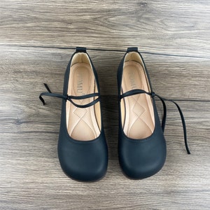 May include: A pair of black leather shoes with a lace-up design. The shoes have a rounded toe and a low heel. The brand name "TOMUL" is printed on the inside of each shoe.