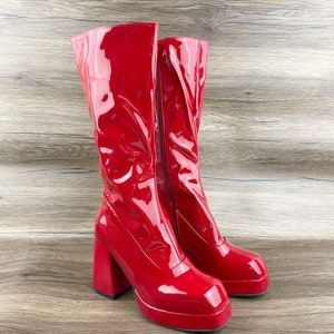 K&ouml;nnte beinhalten: Ein Paar rote Lackleder-Plateau-Stiefel mit einem dicken Absatz.
