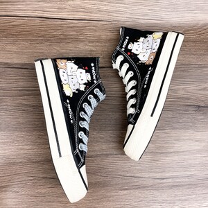 May include: A pair of black high-top canvas shoes with white soles. The shoes feature a cartoon print of cats with the word "meow" repeated on the sides.