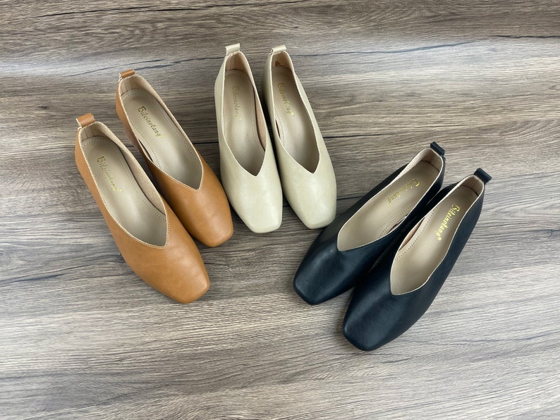 May include: Four pairs of women's flats in black, brown, and beige. The shoes have a pointed toe and a low heel.