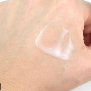 May include: A close-up of a hand with a white, creamy lotion applied to the skin.