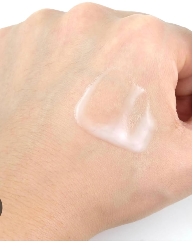 May include: A close-up of a hand with a white, creamy lotion applied to the skin.