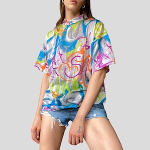 May include: A white ceramic mug with a black handle and the text "But First, Coffee" in a black, bold font. The mug is on a white surface.