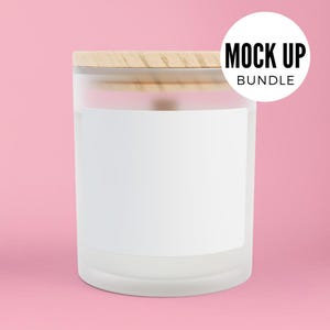 K&ouml;nnte beinhalten: Ein mattes Glas-Kerzengef&auml;&szlig; mit einem Holzdeckel und einem wei&szlig;en Etikett. Das Gef&auml;&szlig; steht auf einem rosafarbenen Hintergrund.
