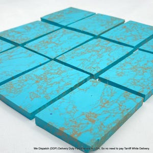 May include: A collection of rectangular turquoise blocks arranged in a grid pattern. Each block features a vibrant cyan blue base colour with intricate, web-like brown veining patterns spread across the flat, smooth surfaces of the material.
