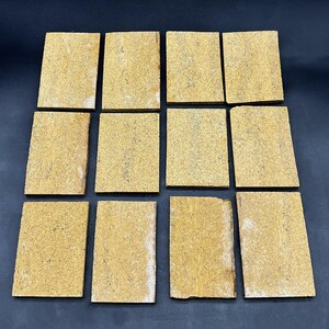 May include: Twelve rectangular, light brown stone tiles with a speckled texture. The tiles are arranged in a grid pattern, with a dark background. The tiles appear to be made of natural stone and are likely for construction or decorative purposes.