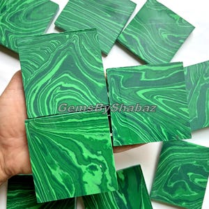 Könnte beinhalten: Eine Sammlung quadratischer Malachitsteine mit leuchtend grüner Farbe und einzigartigen Wirbelmustern. Die Steine sind auf einer weißen Oberfläche angeordnet, mit dem Text "GemsByShabaz" in der unteren rechten Ecke.