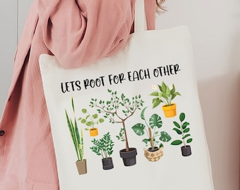 May include: A white tote bag with the text "Let's Root For Each Other" and a graphic of potted plants.