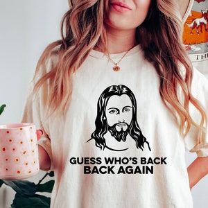 May include: A white t-shirt with a black and white image of Jesus and the text "Guess who's back back again".