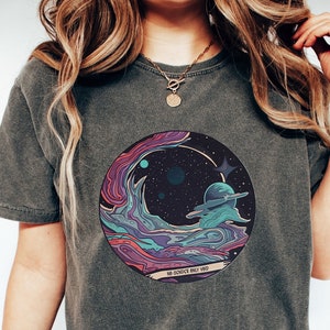May include: A dark gray t-shirt with a colorful graphic of a galaxy with planets and stars. The graphic is in a circle with the text "No worries only vibes" at the bottom.