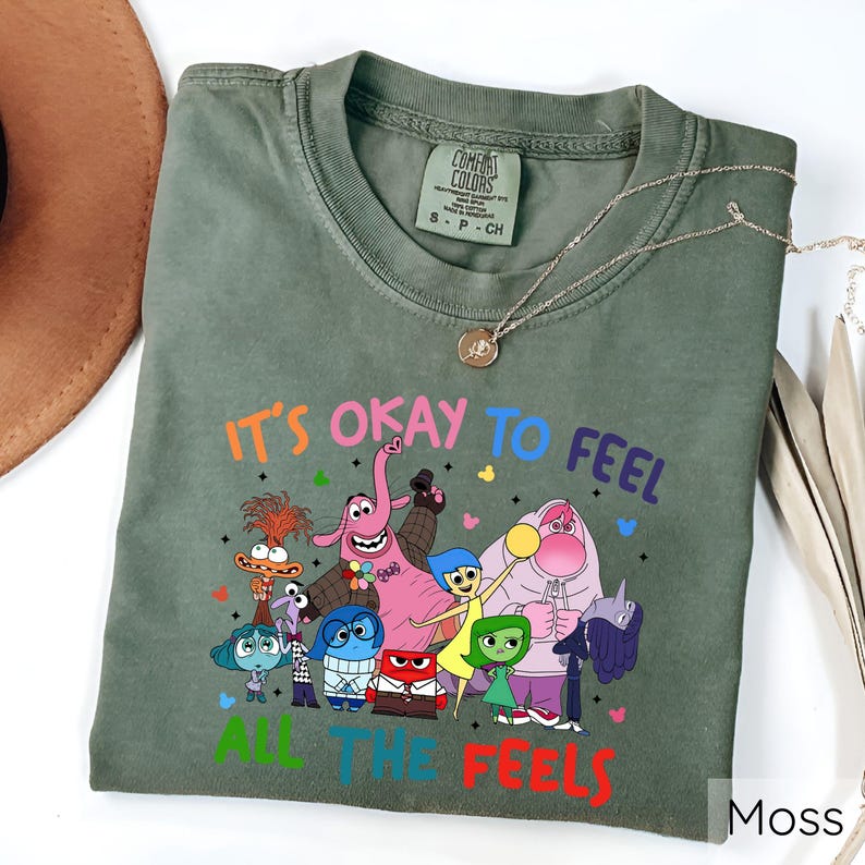 May include: Green t-shirt with a graphic of characters from the movie Inside Out. The text on the shirt reads "It's okay to feel all the feels".