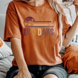 Może przedstawiać: Koszulka w kolorze rdzy z nadrukiem graficznym przedstawiającym krzyż, koronę cierniową i tekst "A lot can happen in 3 days".