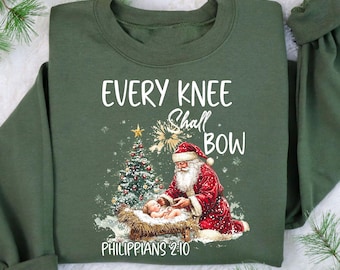 Bluza z nadrukiem "Every Knee Shall Bow", sweter z motywem szopki, bluza z motywem Świętego Mikołaja, bluza z kapturem z klęczącym Mikołajem, bluza z Dzieciątkiem Jezus