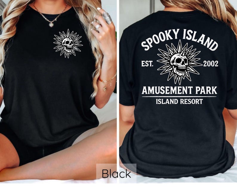 May include: Black t-shirt featuring a white skull design within a sunburst on the front and back. The back of the shirt displays the text "Spooky Island Amusement Park Island Resort" with the establishment year "2002".
