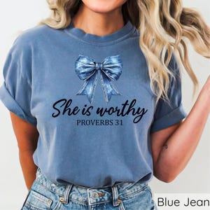 May include: A blue jean t-shirt with a denim bow and the text "She is worthy Proverbs 31" printed on the front.