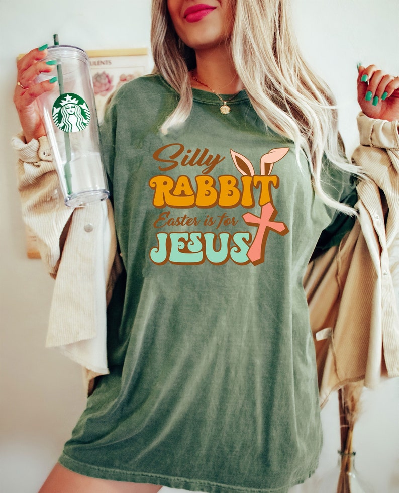 May include: A green t-shirt with a retro-style graphic that says "Silly Rabbit Easter is for Jesus" with a pink cross and bunny ears.