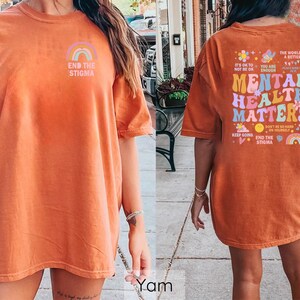 May include: Orange t-shirt with a rainbow and the text "End the Stigma" on the front and a colorful graphic with the text "Mental Health Matters" on the back.