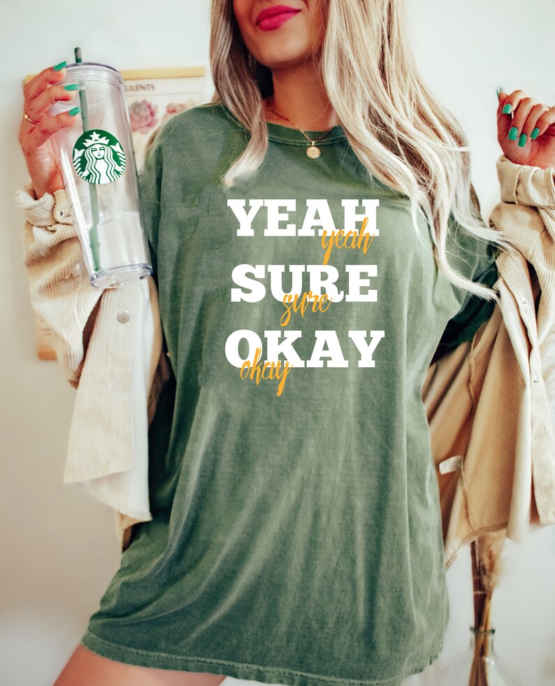 May include: A green t-shirt with the text "YEAH SURE OKAY" in white with the words "yeah" and "okay" in gold.
