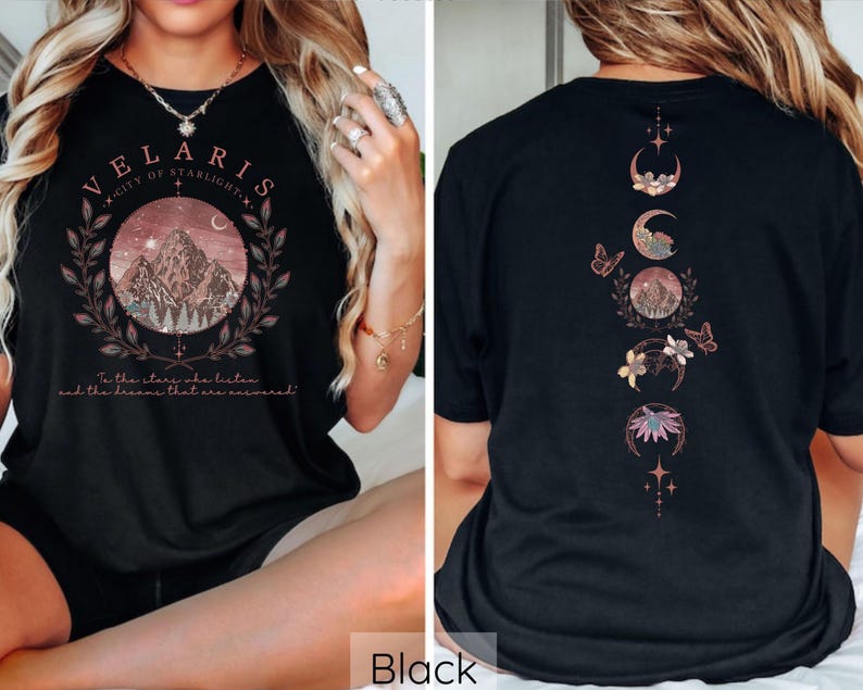May include: Black t-shirt with a graphic print of a mountain range and the text "VELARIS CITY OF STARLIGHT" and "To the stars we listen and the dreams that are answered". The back of the shirt features a vertical design of crescent moons with floral and butterfly accents.