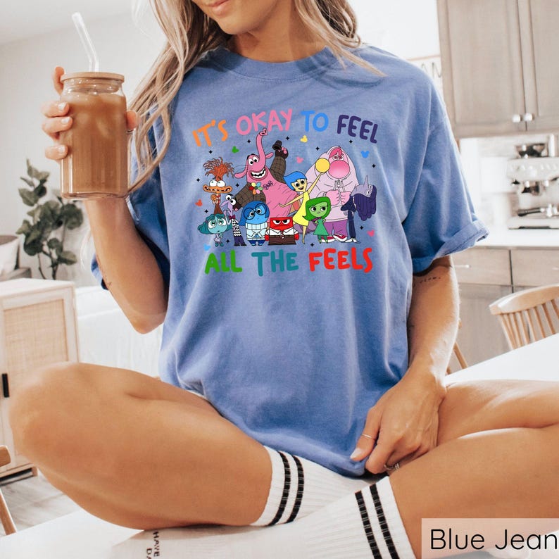 May include: A blue t-shirt with a graphic of characters from the movie Inside Out. The text on the shirt reads "It's okay to feel all the feels."