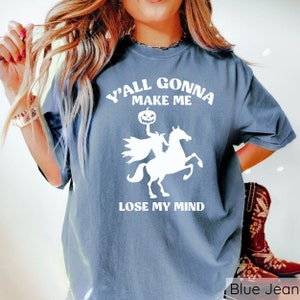 May include: A blue jean t-shirt with a white graphic of a headless horseman riding a horse. The graphic includes a pumpkin head and the text "Y'all gonna make me lose my mind".