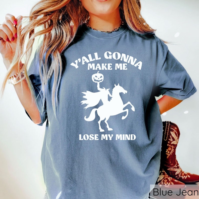 May include: A blue jean t-shirt with a white graphic of a headless horseman riding a horse. The graphic includes a pumpkin head and the text "Y'all gonna make me lose my mind".