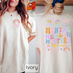 May include: Ivory t-shirt with a rainbow and the text "End the Stigma" on the front and a colorful graphic with the text "Mental Health Matters" on the back.
