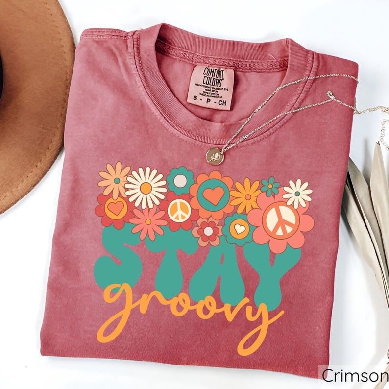 May include: Crimson red t-shirt with a vintage-style graphic that says "Stay groovy" with a peace sign and flowers.