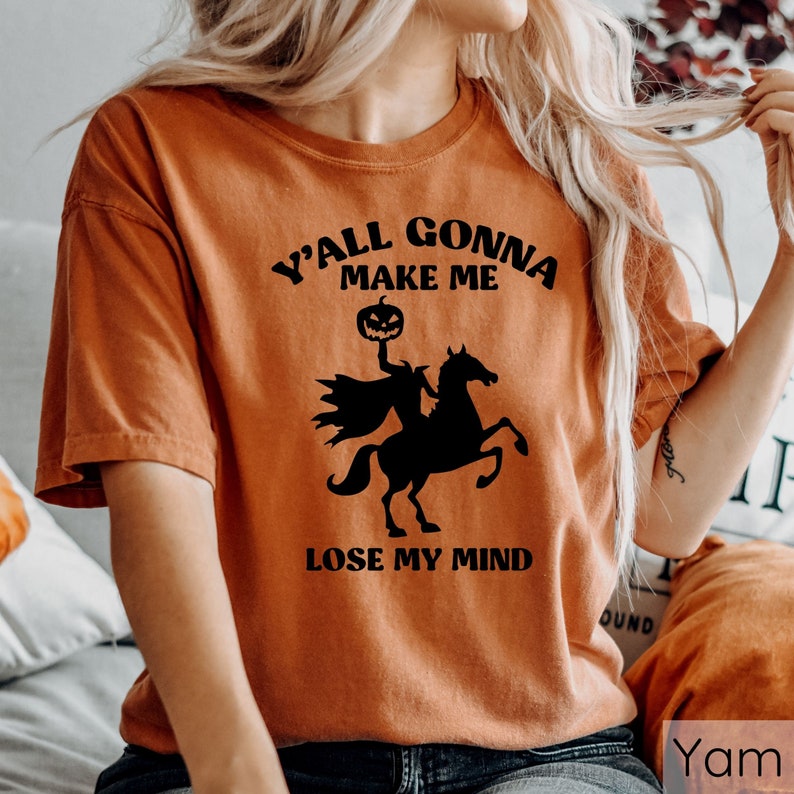 May include: Orange t-shirt with a black graphic of a headless horseman riding a horse. The graphic includes a pumpkin head and the text "Y'all gonna make me lose my mind".